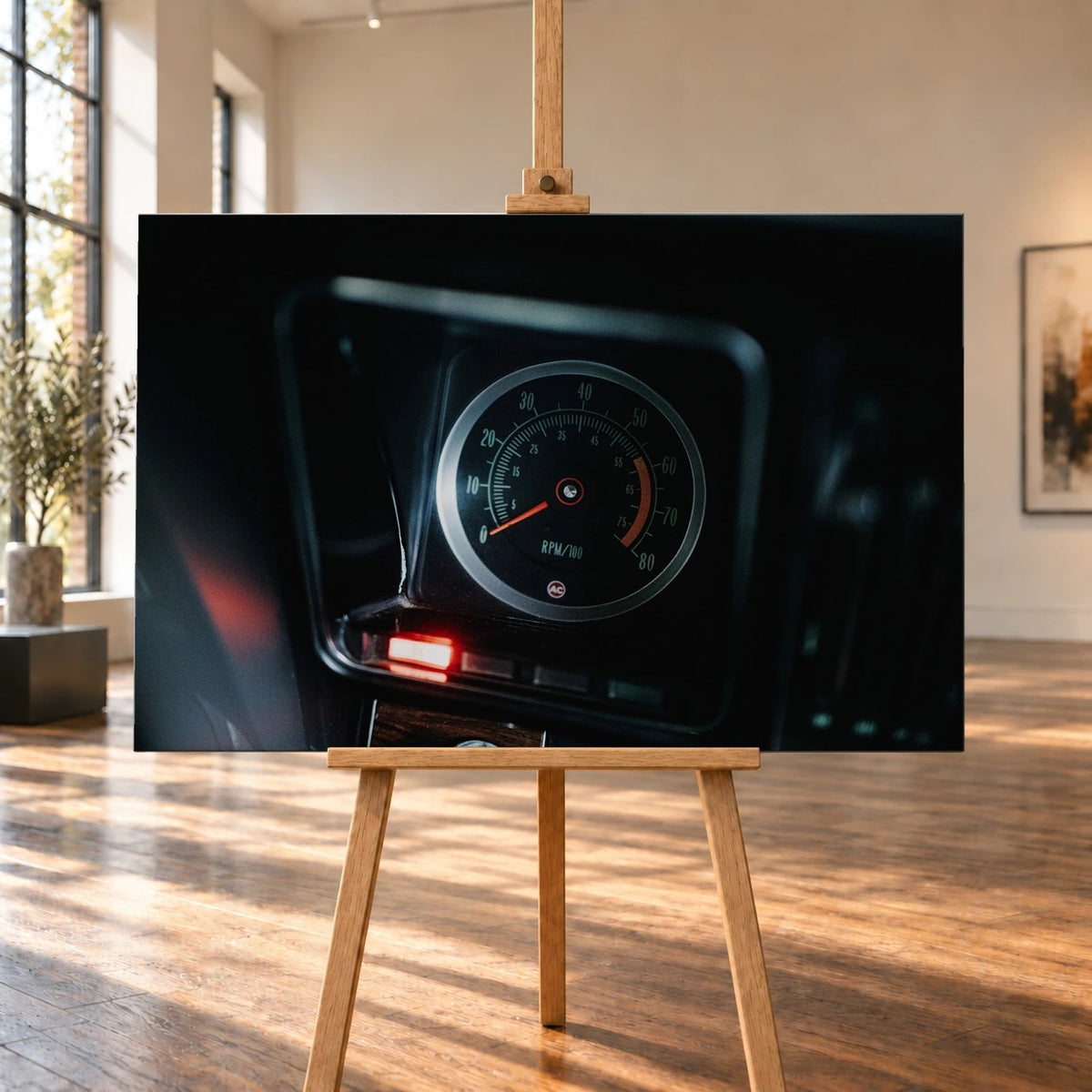 Ein einzelner Rundinstrument-Zähler leuchtet im dunklen Innenraum des Camaro Yenko; rote Kontrollleuchte und Skala sind klar sichtbar. Motiv „Silver Moment“ als Leinwand-Wandbild, auf einer Holzstaffelei in einem hellen Galerieraum.