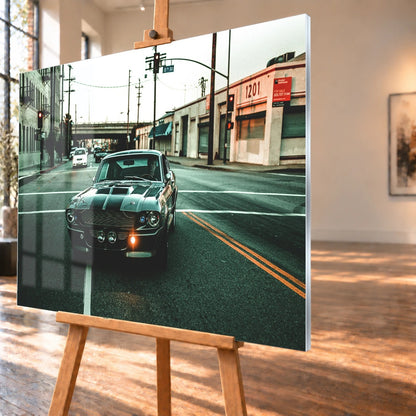 Eleanor fährt frontal über eine leere Stadtstraße; Laternen, Industriegebäude und kühles Morgenlicht rahmen die Doppelstreifen ein. Motiv „Screen Echo 2“ als Acrylglas-Wandbild, schräg von der Seite auf einer Holzstaffelei.