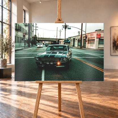 Eleanor fährt frontal über eine leere Stadtstraße; Laternen, Industriegebäude und kühles Morgenlicht rahmen die Doppelstreifen ein. Motiv „Screen Echo 2“ als Alu gebürstet-Wandbild, auf einer Holzstaffelei in einem hellen Galerieraum.