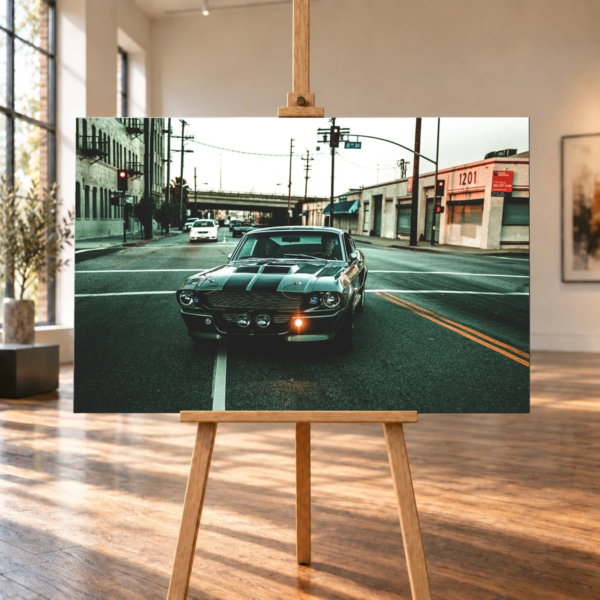 Eleanor fährt frontal über eine leere Stadtstraße; Laternen, Industriegebäude und kühles Morgenlicht rahmen die Doppelstreifen ein. Motiv „Screen Echo 2“ als Leinwand-Wandbild, auf einer Holzstaffelei in einem hellen Galerieraum.