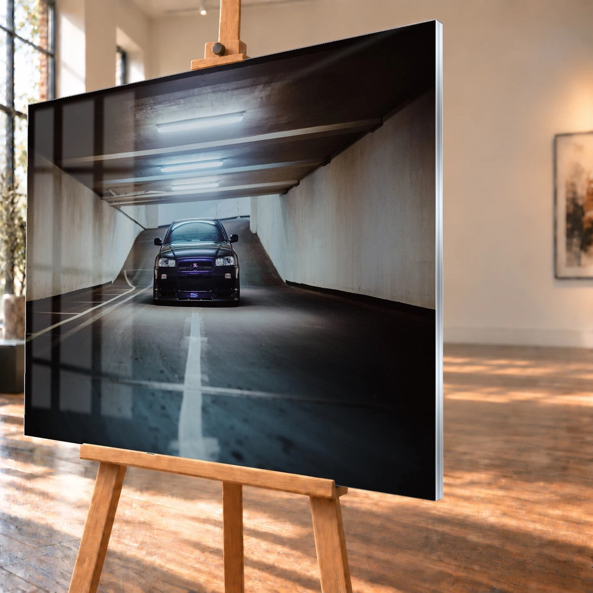 Der violette Nissan Skyline R34 steht frontal und klein am Ende einer langen, symmetrischen Parkhaustunnel-Achse; die helle Mittellinie führt direkt auf das Fahrzeug zu. Motiv „Purple Depth“ als Acrylglas-Wandbild, schräg von der Seite auf einer Holzstaffelei.