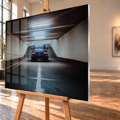 Der violette Nissan Skyline R34 steht frontal und klein am Ende einer langen, symmetrischen Parkhaustunnel-Achse; die helle Mittellinie führt direkt auf das Fahrzeug zu. Motiv „Purple Depth“ als Acrylglas-Wandbild, schräg von der Seite auf einer Holzstaffelei.