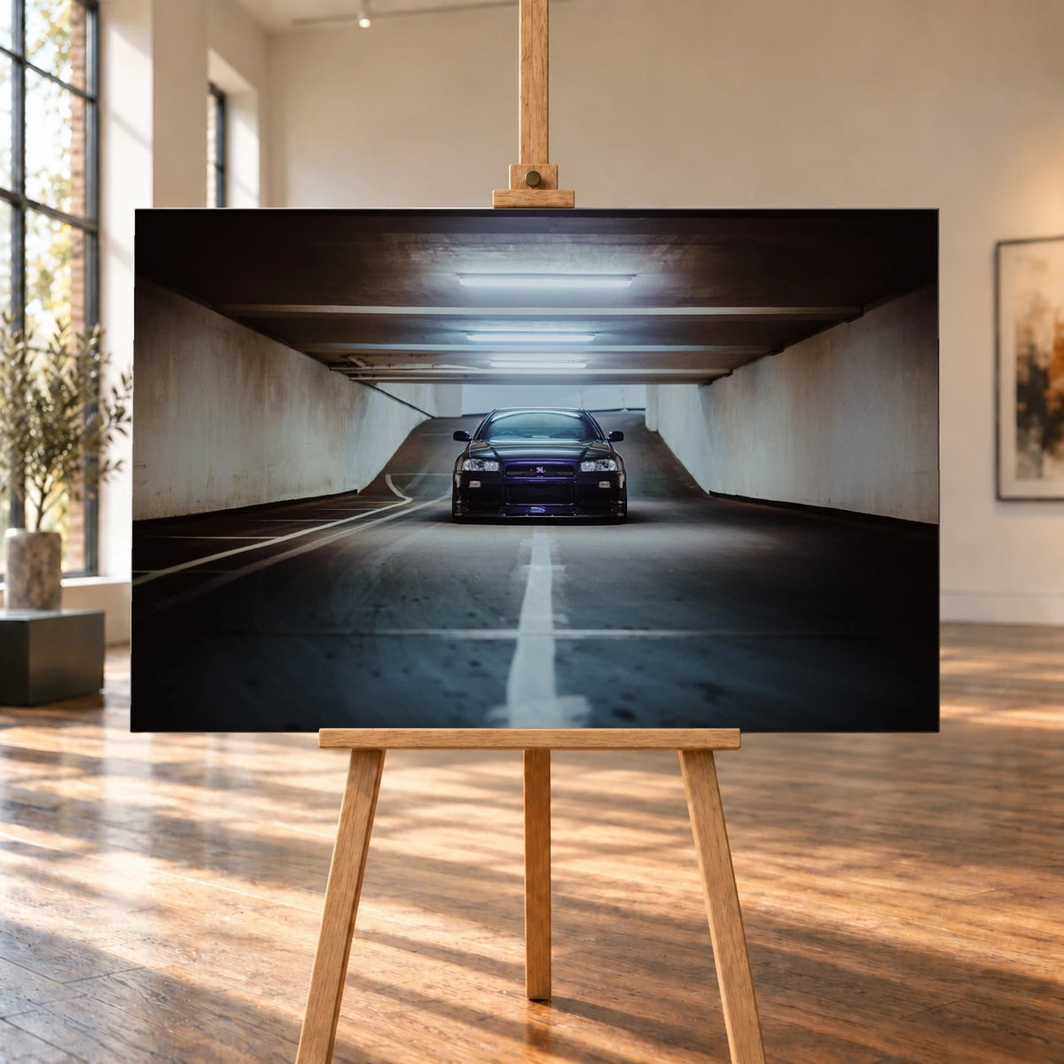 Der violette Nissan Skyline R34 steht frontal und klein am Ende einer langen, symmetrischen Parkhaustunnel-Achse; die helle Mittellinie führt direkt auf das Fahrzeug zu. Motiv „Purple Depth“ als Leinwand-Wandbild, auf einer Holzstaffelei in einem hellen Galerieraum.