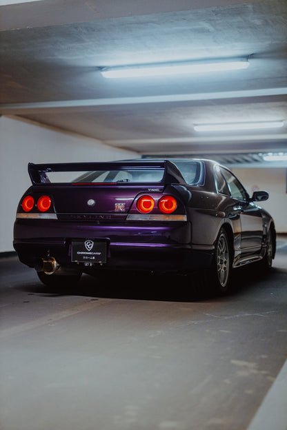 Der Nissan Skyline R33 ist hochkant von hinten fotografiert; die vier roten Rundlichter leuchten unter langen Neonröhren. Originalmotiv „Neon Spirit“ im Hochformat.