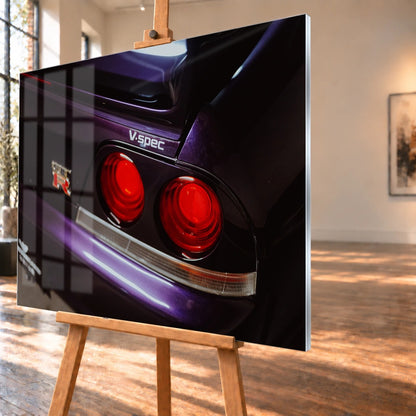 Eine enge Heckaufnahme zeigt zwei rote Rundlichter, GT-R- und V-Spec-Schriftzug sowie den violetten Lack des Nissan Skyline R33. Motiv „Neon Presence“ als Acrylglas-Wandbild, schräg von der Seite auf einer Holzstaffelei.