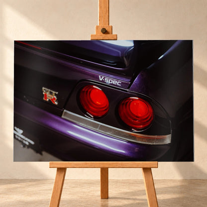 Eine enge Heckaufnahme zeigt zwei rote Rundlichter, GT-R- und V-Spec-Schriftzug sowie den violetten Lack des Nissan Skyline R33. Motiv „Neon Presence“ als Alu gebürstet-Wandbild, frontal auf einer Holzstaffelei.
