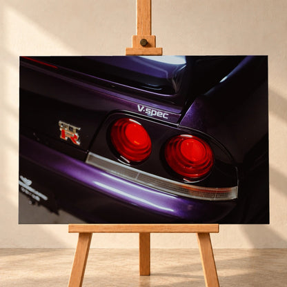Eine enge Heckaufnahme zeigt zwei rote Rundlichter, GT-R- und V-Spec-Schriftzug sowie den violetten Lack des Nissan Skyline R33. Motiv „Neon Presence“ als Leinwand-Wandbild, frontal auf einer Holzstaffelei.