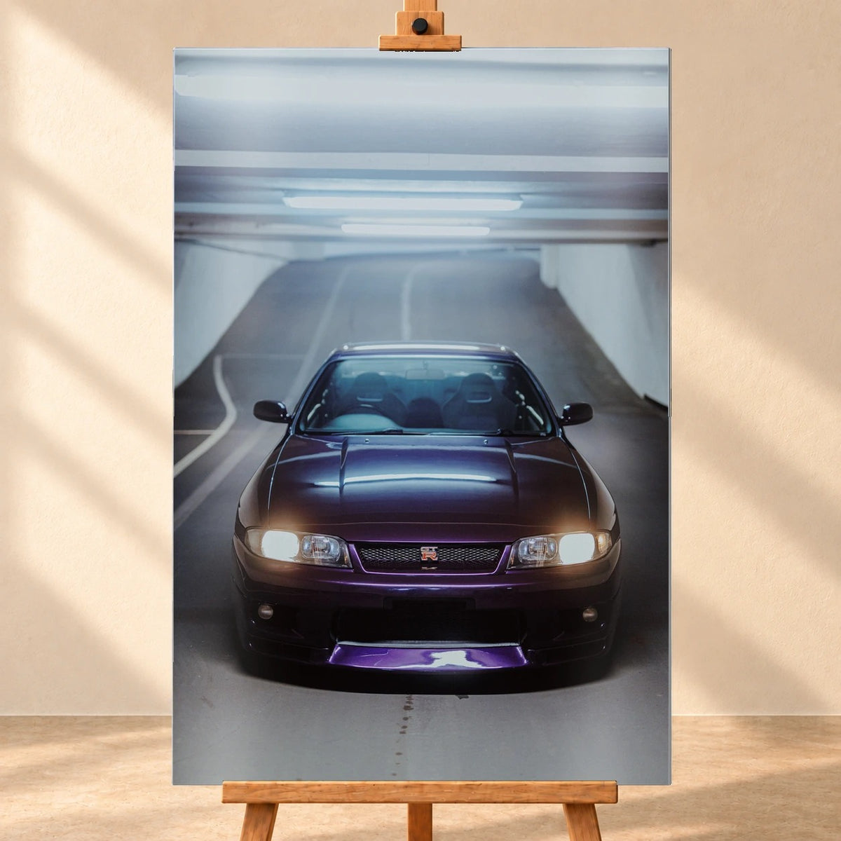 Die Front des Nissan Skyline R33 füllt das Hochformat; Scheinwerfer, Kühlergrill und der violette Frontsplitter liegen im kalten Deckenlicht. Motiv „Neon Pulse“ als Alu gebürstet-Wandbild, frontal auf einer Holzstaffelei.