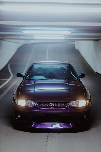 Die Front des Nissan Skyline R33 füllt das Hochformat; Scheinwerfer, Kühlergrill und der violette Frontsplitter liegen im kalten Deckenlicht. Originalmotiv „Neon Pulse“ im Hochformat.