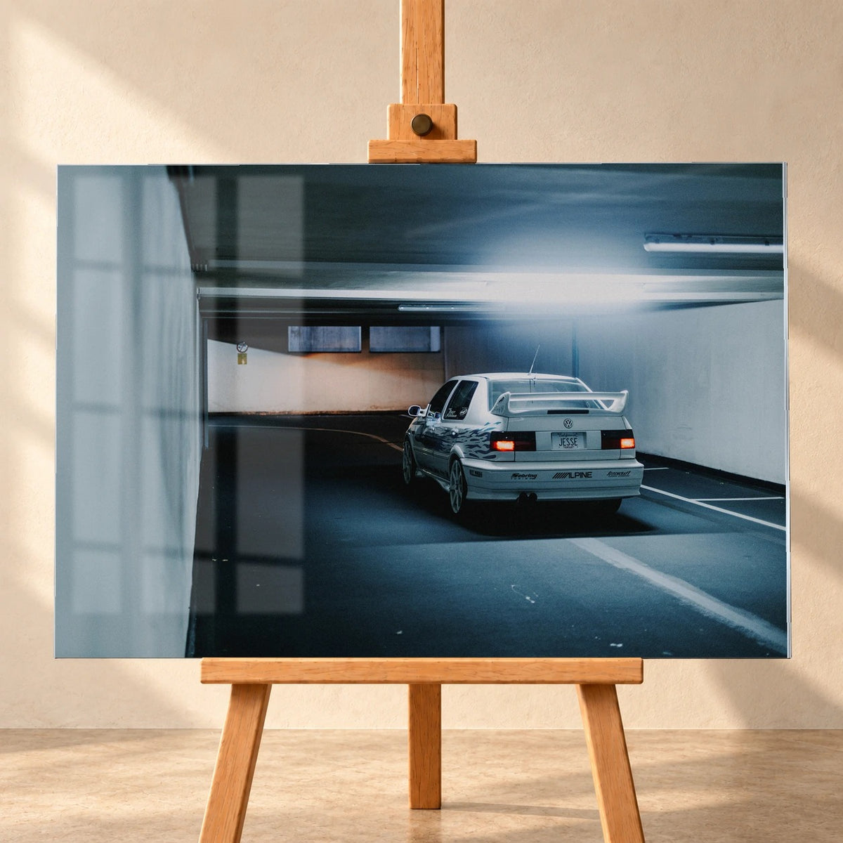 Jesses Jetta ist von hinten in einer langen Parkhausspur aufgenommen; die weiße Karosserie hebt sich klein vom kühlen Tunnel ab. Motiv „Screen Presence“ als Acrylglas-Wandbild, frontal auf einer Holzstaffelei.