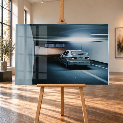 Jesses Jetta ist von hinten in einer langen Parkhausspur aufgenommen; die weiße Karosserie hebt sich klein vom kühlen Tunnel ab. Motiv „Screen Presence“ als Acrylglas-Wandbild, auf einer Holzstaffelei in einem hellen Galerieraum.