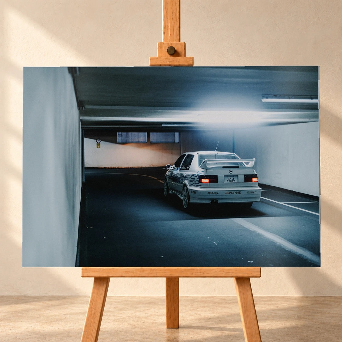 Jesses Jetta ist von hinten in einer langen Parkhausspur aufgenommen; die weiße Karosserie hebt sich klein vom kühlen Tunnel ab. Motiv „Screen Presence“ als Alu gebürstet-Wandbild, frontal auf einer Holzstaffelei.