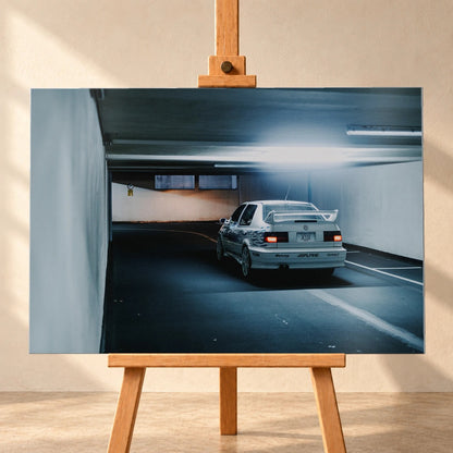 Jesses Jetta ist von hinten in einer langen Parkhausspur aufgenommen; die weiße Karosserie hebt sich klein vom kühlen Tunnel ab. Motiv „Screen Presence“ als Alu gebürstet-Wandbild, frontal auf einer Holzstaffelei.