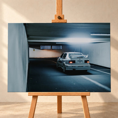Jesses Jetta ist von hinten in einer langen Parkhausspur aufgenommen; die weiße Karosserie hebt sich klein vom kühlen Tunnel ab. Motiv „Screen Presence“ als Leinwand-Wandbild, frontal auf einer Holzstaffelei.