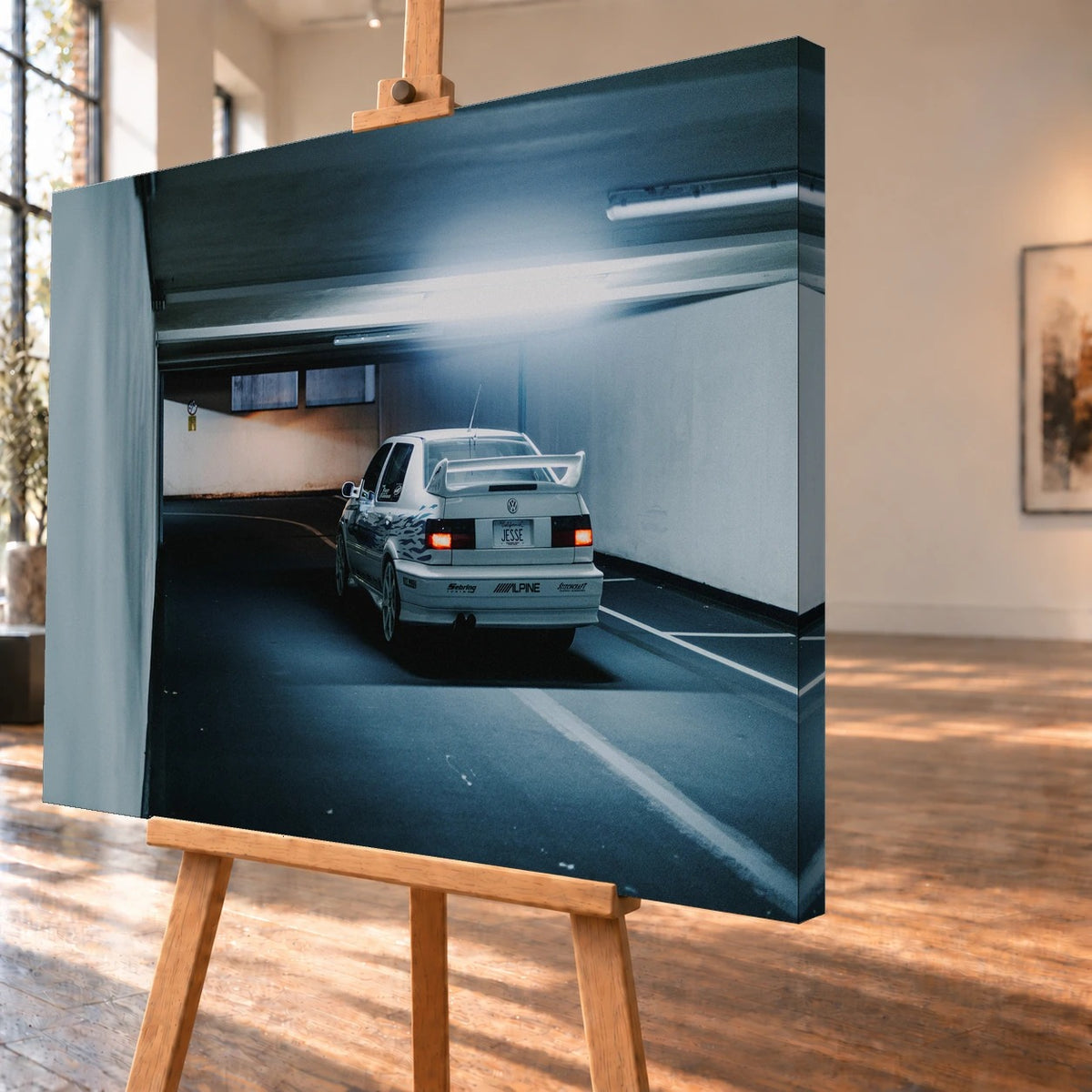 Jesses Jetta ist von hinten in einer langen Parkhausspur aufgenommen; die weiße Karosserie hebt sich klein vom kühlen Tunnel ab. Motiv „Screen Presence“ als Leinwand-Wandbild, schräg von der Seite auf einer Holzstaffelei.