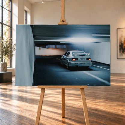 Jesses Jetta ist von hinten in einer langen Parkhausspur aufgenommen; die weiße Karosserie hebt sich klein vom kühlen Tunnel ab. Motiv „Screen Presence“ als Leinwand-Wandbild, auf einer Holzstaffelei in einem hellen Galerieraum.