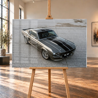 Eleanor ist aus erhöhter Perspektive schräg von vorn zu sehen; silberne Karosserie und schwarze Doppelstreifen füllen die freie Asphaltfläche. Motiv „Cinematic Pulse“ als Acrylglas-Wandbild, auf einer Holzstaffelei in einem hellen Galerieraum.