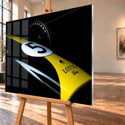 Eine enge, fast abstrakte Detailaufnahme zeigt grün-gelbe Lotus-49-Lackierung, weiße Startnummer und Reifenflanke vor schwarzem Hintergrund. Motiv „Fast Moment“ als Acrylglas-Wandbild, schräg von der Seite auf einer Holzstaffelei.