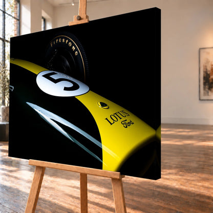Eine enge, fast abstrakte Detailaufnahme zeigt grün-gelbe Lotus-49-Lackierung, weiße Startnummer und Reifenflanke vor schwarzem Hintergrund. Motiv „Fast Moment“ als Leinwand-Wandbild, schräg von der Seite auf einer Holzstaffelei.