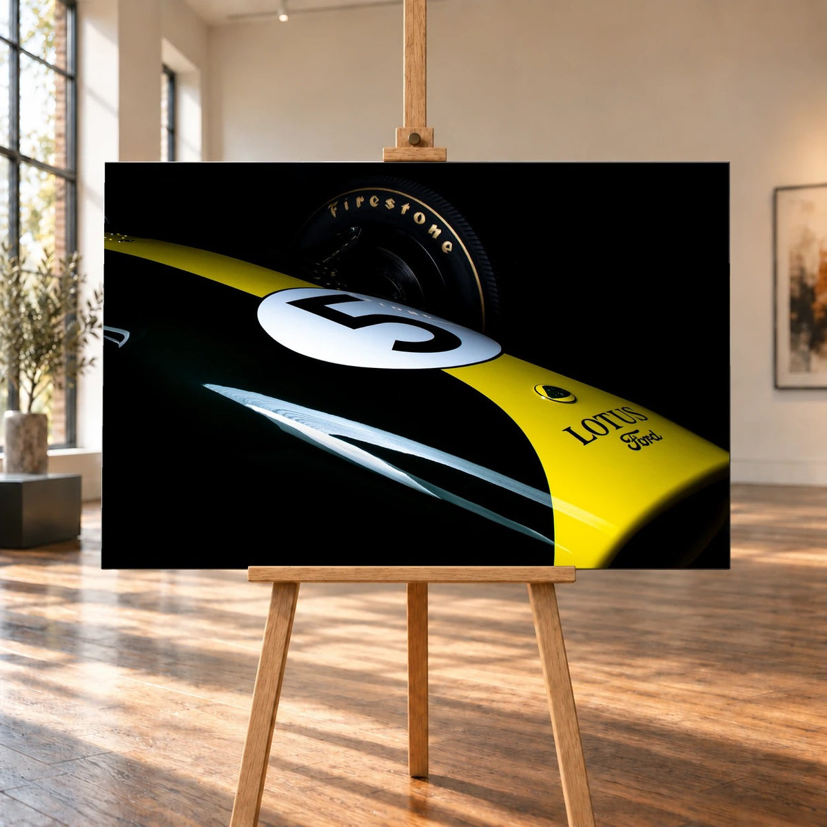 Eine enge, fast abstrakte Detailaufnahme zeigt grün-gelbe Lotus-49-Lackierung, weiße Startnummer und Reifenflanke vor schwarzem Hintergrund. Motiv „Fast Moment“ als Leinwand-Wandbild, auf einer Holzstaffelei in einem hellen Galerieraum.