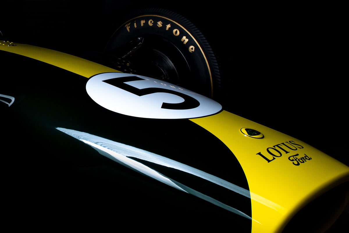 Eine enge, fast abstrakte Detailaufnahme zeigt grün-gelbe Lotus-49-Lackierung, weiße Startnummer und Reifenflanke vor schwarzem Hintergrund. Originalmotiv „Fast Moment“ im Querformat.