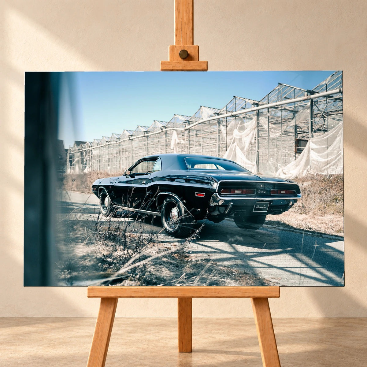 Der schwarze Dodge Challenger ist schräg von hinten auf einem Industriegelände aufgenommen; breite Karosserie und rote Rückleuchten wirken kraftvoll. Motiv „Timeless Pulse“ als Leinwand-Wandbild, frontal auf einer Holzstaffelei.