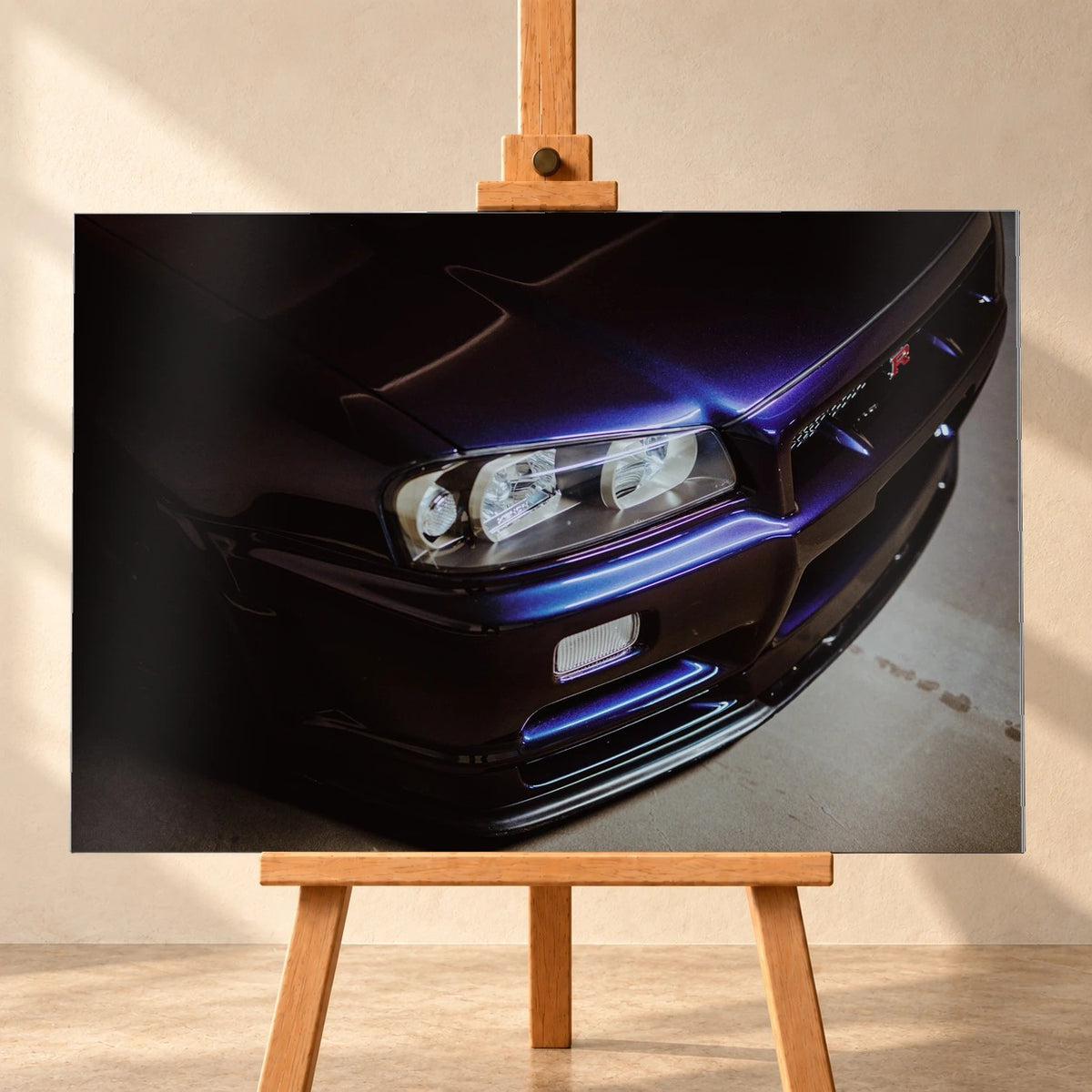 Eine schräge Nahaufnahme zeigt Scheinwerfer, Frontschürze und violette Lackkante des Nissan Skyline R34 unter hartem Neonlicht. Motiv „Skyline Presence“ als Alu gebürstet-Wandbild, frontal auf einer Holzstaffelei.