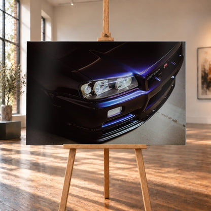 Eine schräge Nahaufnahme zeigt Scheinwerfer, Frontschürze und violette Lackkante des Nissan Skyline R34 unter hartem Neonlicht. Motiv „Skyline Presence“ als Alu gebürstet-Wandbild, auf einer Holzstaffelei in einem hellen Galerieraum.