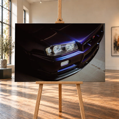 Eine schräge Nahaufnahme zeigt Scheinwerfer, Frontschürze und violette Lackkante des Nissan Skyline R34 unter hartem Neonlicht. Motiv „Skyline Presence“ als Leinwand-Wandbild, auf einer Holzstaffelei in einem hellen Galerieraum.