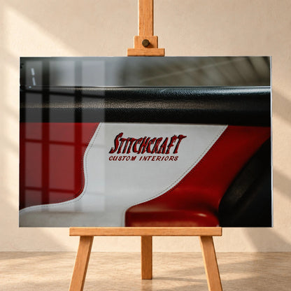 Die Nahaufnahme zeigt den rot-weißen Innenraumbezug mit Stitchcraft-Schriftzug; Material, Naht und Farbe stehen im Mittelpunkt. Motiv „Cinematic Horizon“ als Acrylglas-Wandbild, frontal auf einer Holzstaffelei.