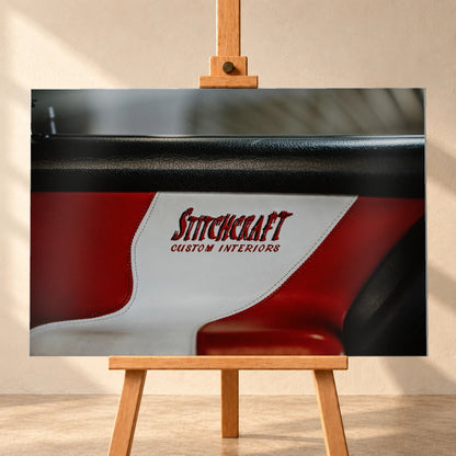 Die Nahaufnahme zeigt den rot-weißen Innenraumbezug mit Stitchcraft-Schriftzug; Material, Naht und Farbe stehen im Mittelpunkt. Motiv „Cinematic Horizon“ als Alu gebürstet-Wandbild, frontal auf einer Holzstaffelei.