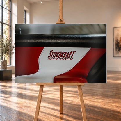 Die Nahaufnahme zeigt den rot-weißen Innenraumbezug mit Stitchcraft-Schriftzug; Material, Naht und Farbe stehen im Mittelpunkt. Motiv „Cinematic Horizon“ als Alu gebürstet-Wandbild, auf einer Holzstaffelei in einem hellen Galerieraum.