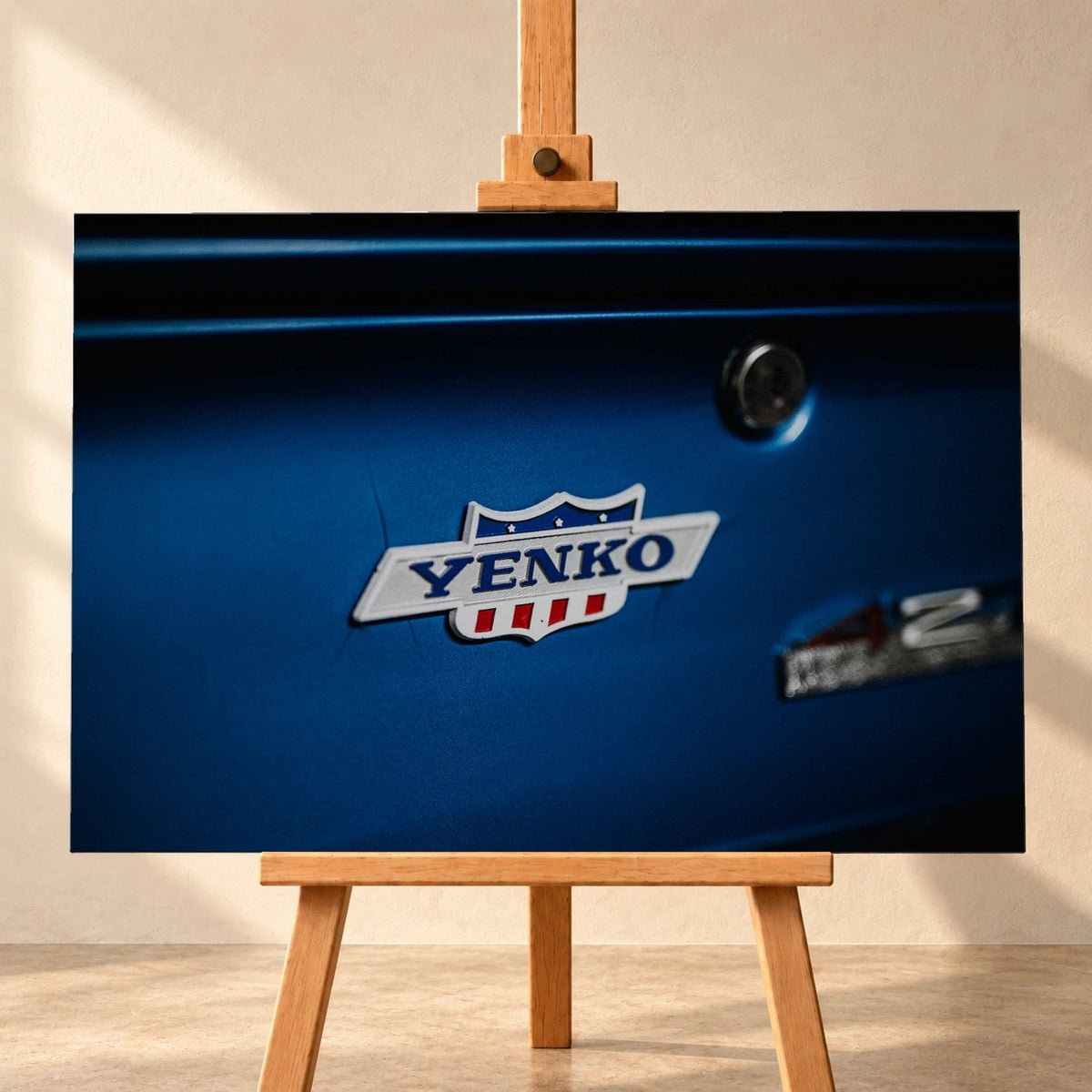 Das Yenko-Emblem sitzt als helles Detail auf der blauen Karosserie; Lack, Chrom und Schriftzug füllen die Aufnahme. Motiv „Hero Line“ als Leinwand-Wandbild, frontal auf einer Holzstaffelei.