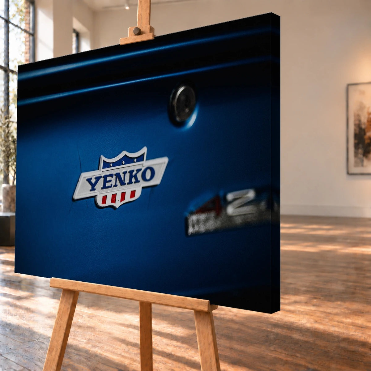 Das Yenko-Emblem sitzt als helles Detail auf der blauen Karosserie; Lack, Chrom und Schriftzug füllen die Aufnahme. Motiv „Hero Line“ als Leinwand-Wandbild, schräg von der Seite auf einer Holzstaffelei.