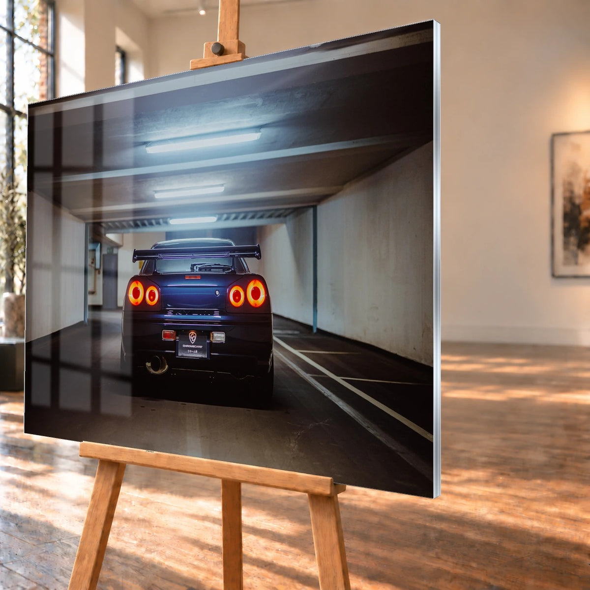 Der Nissan Skyline R34 ist exakt mittig von hinten aufgenommen; vier leuchtende Rundlichter und die geraden Parkhauslinien rahmen ihn ein. Motiv „Neon Rhythm“ als Acrylglas-Wandbild, schräg von der Seite auf einer Holzstaffelei.