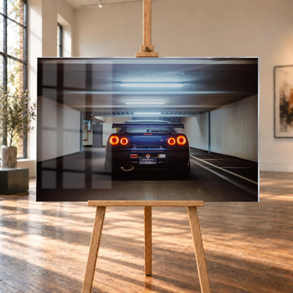 Der Nissan Skyline R34 ist exakt mittig von hinten aufgenommen; vier leuchtende Rundlichter und die geraden Parkhauslinien rahmen ihn ein. Motiv „Neon Rhythm“ als Acrylglas-Wandbild, auf einer Holzstaffelei in einem hellen Galerieraum.