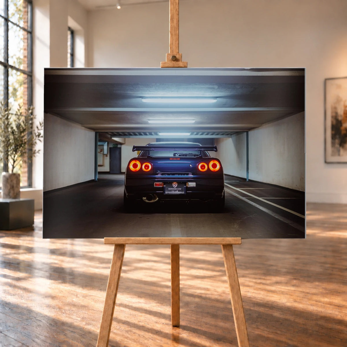 Der Nissan Skyline R34 ist exakt mittig von hinten aufgenommen; vier leuchtende Rundlichter und die geraden Parkhauslinien rahmen ihn ein. Motiv „Neon Rhythm“ als Alu gebürstet-Wandbild, auf einer Holzstaffelei in einem hellen Galerieraum.