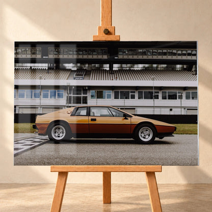 Der goldene Lotus Esprit steht streng im Seitenprofil vor der Boxenanlage; Keilform und dunkle Räder zeichnen eine klare Silhouette. Motiv „Timeless Rhythm“ als Acrylglas-Wandbild, frontal auf einer Holzstaffelei.