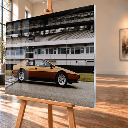 Der goldene Lotus Esprit steht streng im Seitenprofil vor der Boxenanlage; Keilform und dunkle Räder zeichnen eine klare Silhouette. Motiv „Timeless Rhythm“ als Acrylglas-Wandbild, schräg von der Seite auf einer Holzstaffelei.
