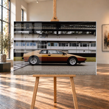 Der goldene Lotus Esprit steht streng im Seitenprofil vor der Boxenanlage; Keilform und dunkle Räder zeichnen eine klare Silhouette. Motiv „Timeless Rhythm“ als Acrylglas-Wandbild, auf einer Holzstaffelei in einem hellen Galerieraum.