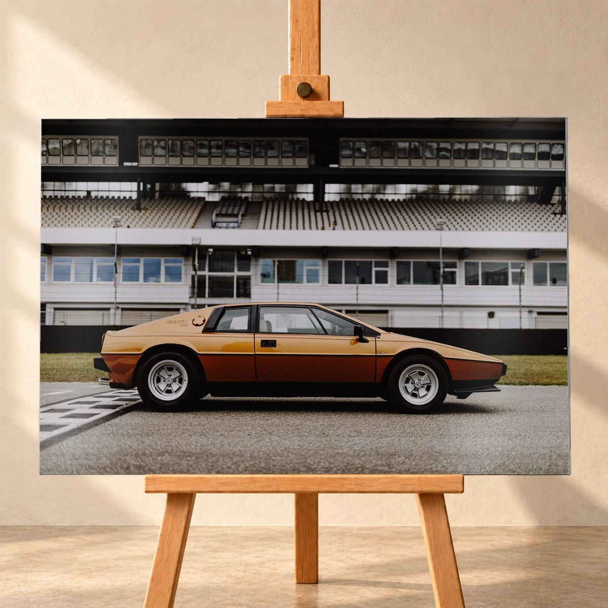Der goldene Lotus Esprit steht streng im Seitenprofil vor der Boxenanlage; Keilform und dunkle Räder zeichnen eine klare Silhouette. Motiv „Timeless Rhythm“ als Alu gebürstet-Wandbild, frontal auf einer Holzstaffelei.