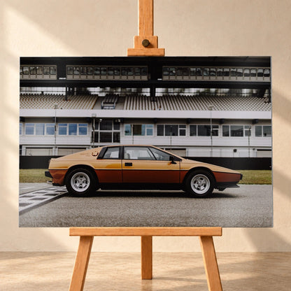 Der goldene Lotus Esprit steht streng im Seitenprofil vor der Boxenanlage; Keilform und dunkle Räder zeichnen eine klare Silhouette. Motiv „Timeless Rhythm“ als Alu gebürstet-Wandbild, frontal auf einer Holzstaffelei.