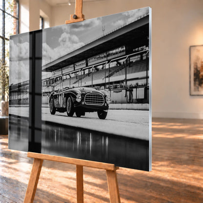 Der MG Tojeiro steht im Schwarz-Weiß-Seitenprofil vor der Boxenanlage; sein Spiegelbild erscheint auf dem nassen Boden. Motiv „Trackside Echo“ als Acrylglas-Wandbild, schräg von der Seite auf einer Holzstaffelei.