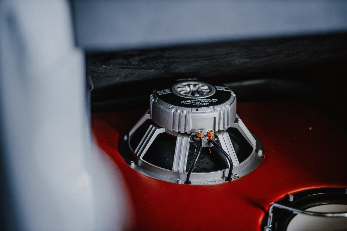 Ein metallischer Schaltknauf steht scharf vor dem rot-weißen Innenraum von Jesses Jetta; geringe Tiefenschärfe isoliert das Detail. Originalmotiv „Night Drive 2“ im Querformat.