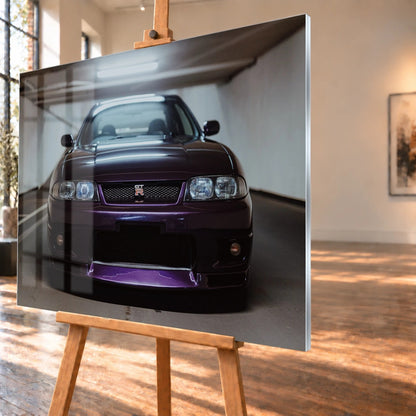 Der Nissan Skyline R33 ist frontal und nah unter Neonlicht fotografiert; Kühlergrill und violetter Splitter bilden eine klare horizontale Linie. Motiv „Skyline Moment“ als Acrylglas-Wandbild, schräg von der Seite auf einer Holzstaffelei.