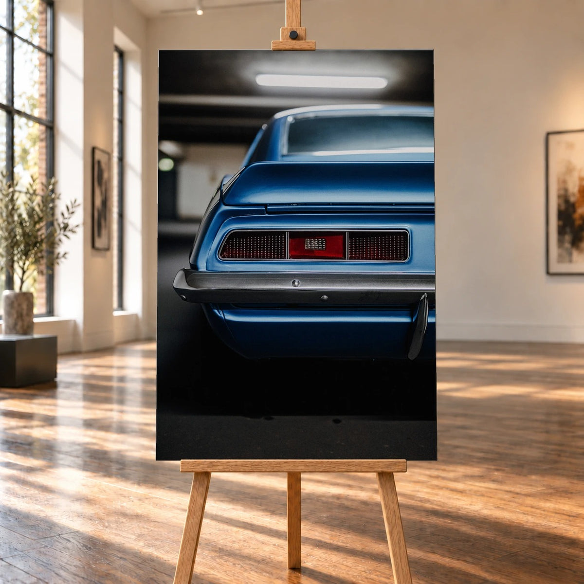 Das Heck des blauen Camaro Yenko ist eng angeschnitten; Rücklicht, Spoilerkante und schwarze Blende bilden horizontale Flächen. Motiv „Screen Focus“ als Leinwand-Wandbild, auf einer Holzstaffelei in einem hellen Galerieraum.