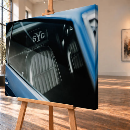 Die Innenraum-Nahaufnahme des blauen Camaro Yenko zeigt den hellen Sitz mit SYC-Schriftzug, eingefasst von Fenster und Karosserie. Motiv „Hero Moment 2“ als Leinwand-Wandbild, schräg von der Seite auf einer Holzstaffelei.
