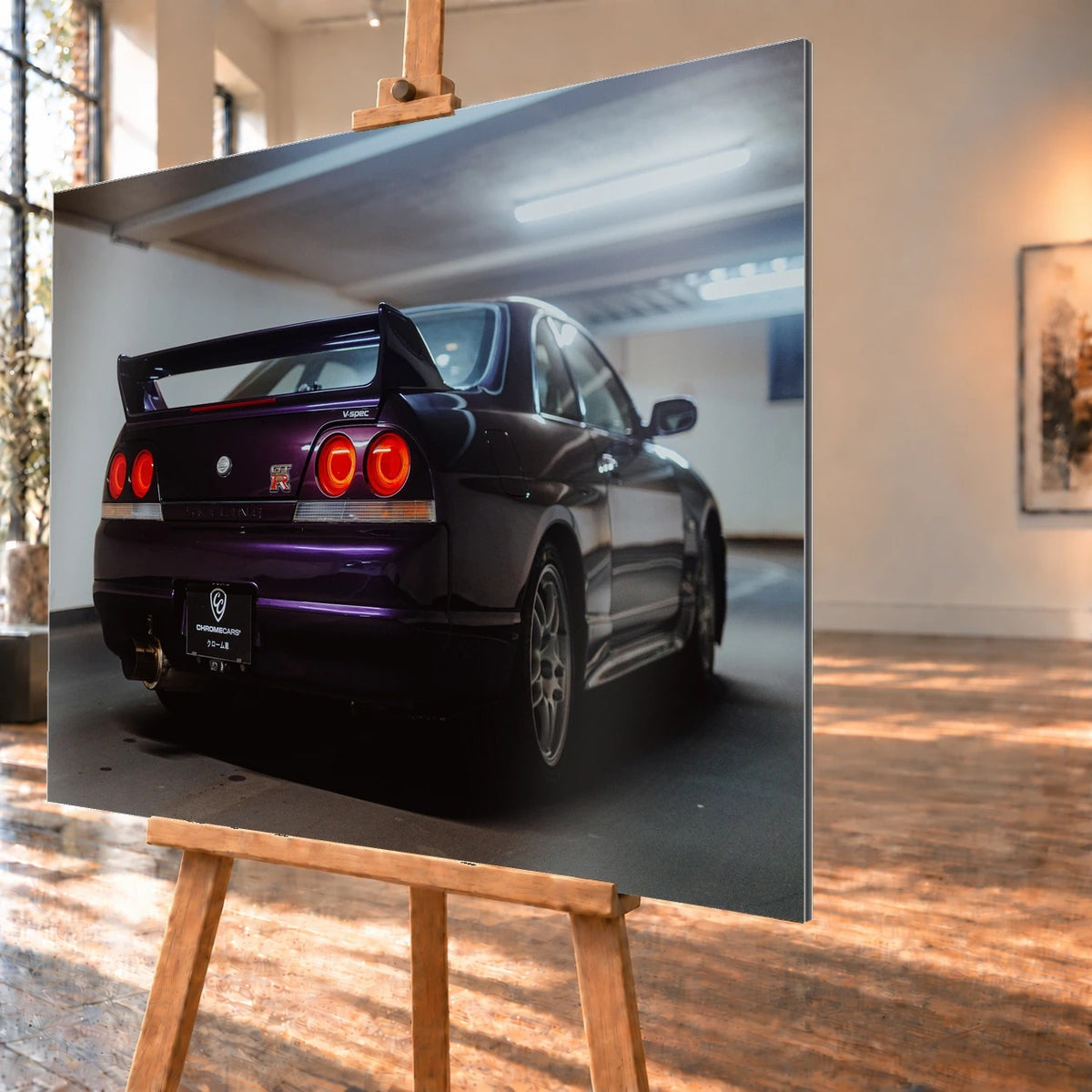 Der Nissan Skyline R33 steht schräg von hinten in einer Parkhauskurve; Rundlichter und Spoiler heben sich vom kühlen Beton ab. Motiv „Neon Story“ als Alu gebürstet-Wandbild, schräg von der Seite auf einer Holzstaffelei.