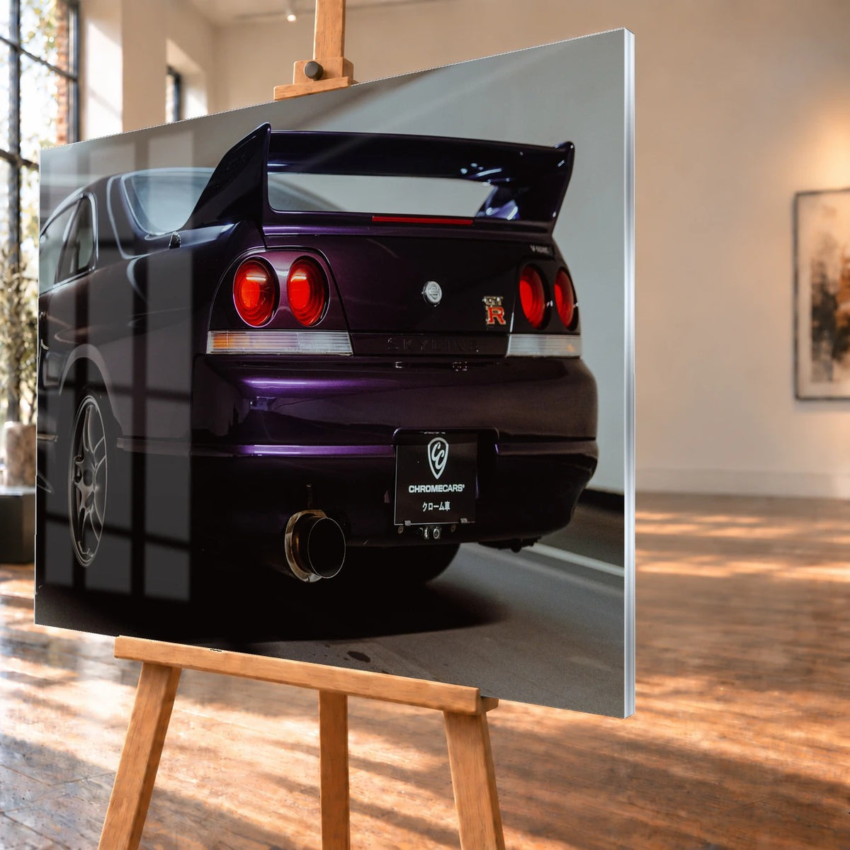 Die niedrige Heckperspektive des Nissan Skyline R33 hebt Spoiler, Rundlichter, Felgen und das große Endrohr hervor. Motiv „Skyline Drive“ als Acrylglas-Wandbild, schräg von der Seite auf einer Holzstaffelei.