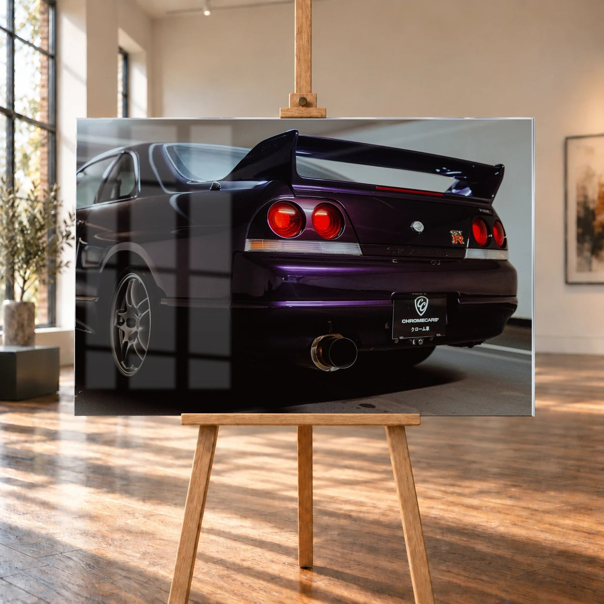 Die niedrige Heckperspektive des Nissan Skyline R33 hebt Spoiler, Rundlichter, Felgen und das große Endrohr hervor. Motiv „Skyline Drive“ als Acrylglas-Wandbild, auf einer Holzstaffelei in einem hellen Galerieraum.